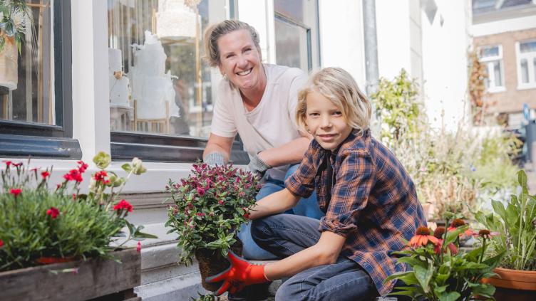 Jonge jongen plant met zijn moeder bloemen in plaats van tegels