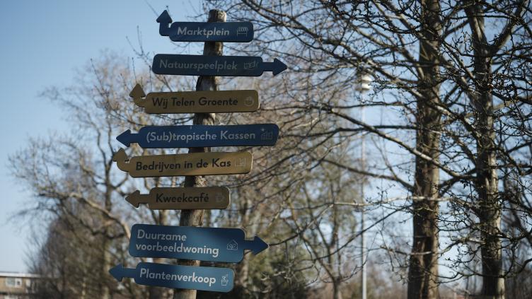 Een paal met wegwijsborden in de Haarlemmer Kweektuin