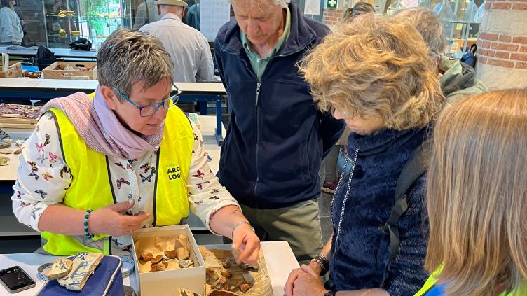 Archeoloog geeft enkele bezoekers uitleg over vondsten