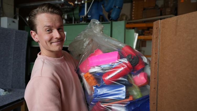 Ezra Koldenhof poseert met een plastic zak vol plastic drinkbekers