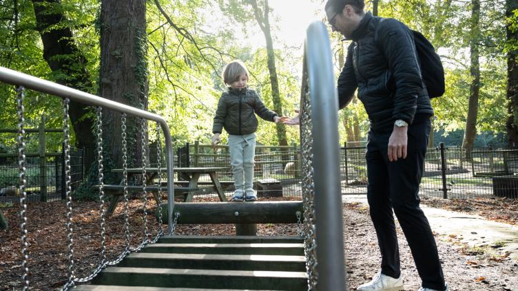 Vader en kind spelen in de speeltuin van kinderboerderij Houthoeve