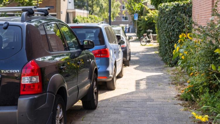 Geparkeerde auto's met 2 wielen op de stoep