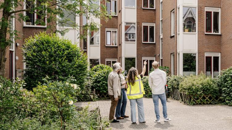 Bewoners staan met een adviseur voor hun appartement