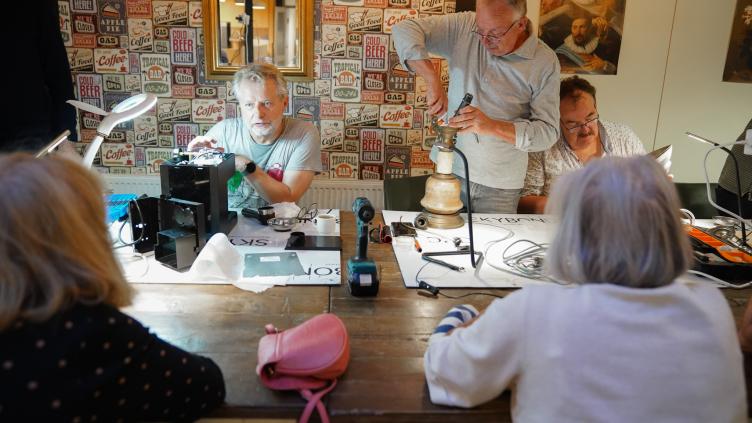 Mensen aan een tafel repareren spullen