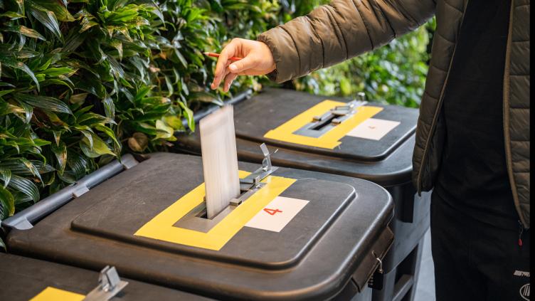 Iemand gooit een stembiljet in de stembus. 