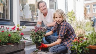 Jonge jongen plant met zijn moeder bloemen in plaats van tegels