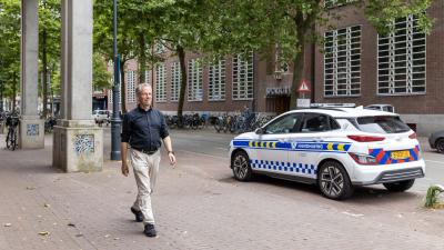 Jaap Meindersma loopt op straat langs een auto van handhaving
