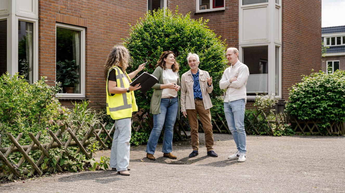 3 bewoners en 1 adviseur staan voor een appartementencomplex