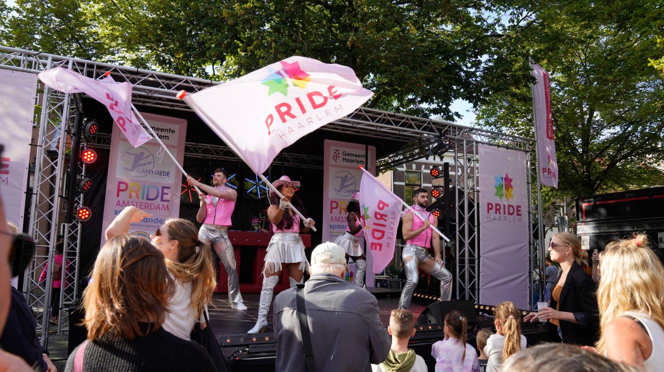 Personen met Pride-vlag op een podium. 