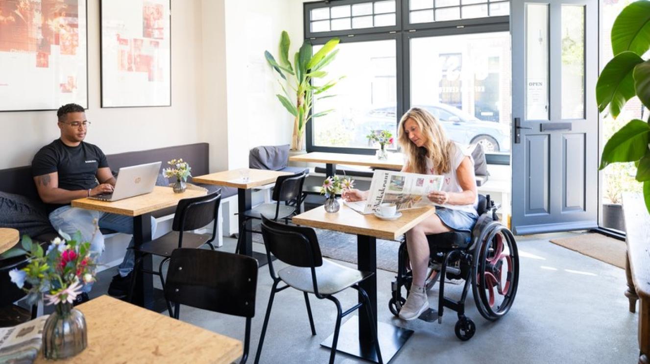 Vrouw in rolstoel in een café.