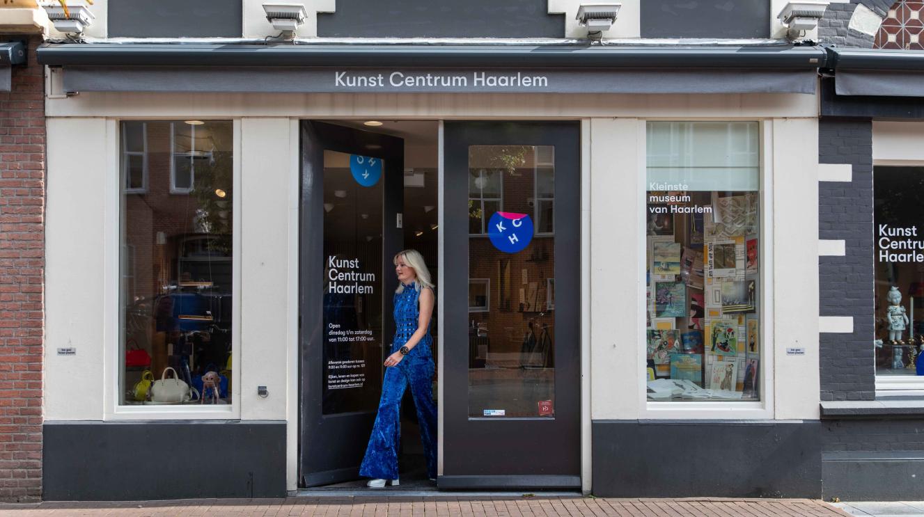 Vrouw in blauw pak loopt uit een winkelpand