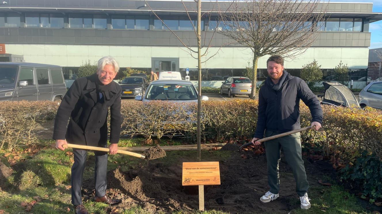 Wethouder Robbert Berkhout en voorzitter Bruno Giebels planten samen een boom bij het kantoor van Parkmanagement Waarderpolder. 