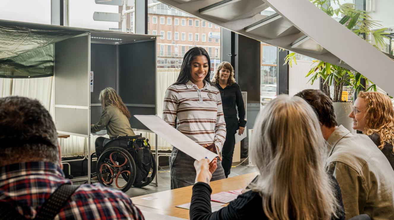 Leden van een stembureau met 3 Haarlemmers die komen stemmen