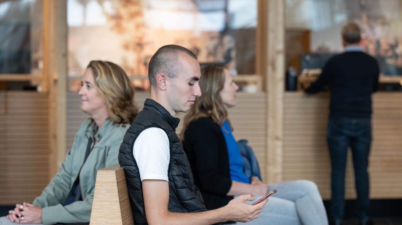 Drie mensen die wachten in de publiekshal en een vierde persoon die al geholpen wordt
