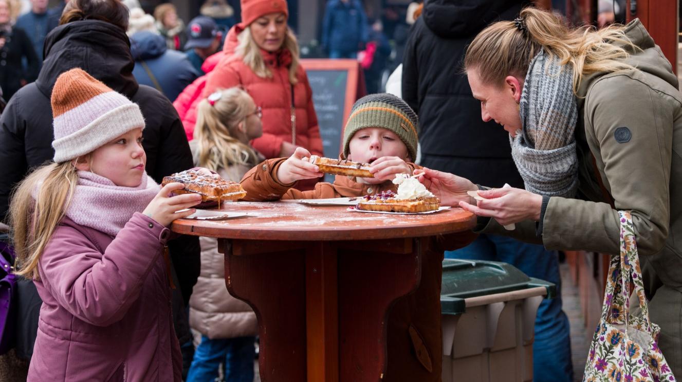 Kinderen eten een wafel op de kerstmarkt