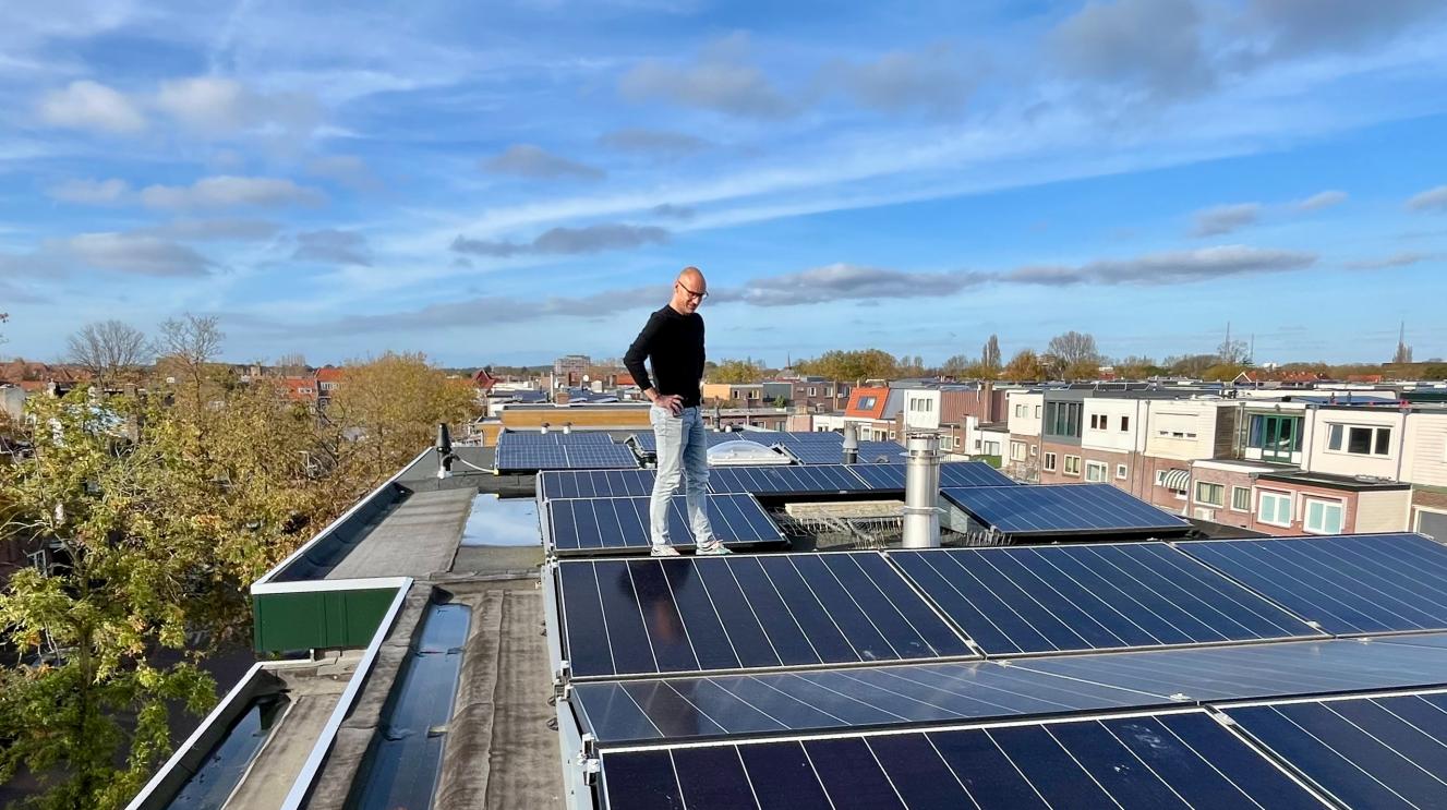man op het dak bij zonnepanelen