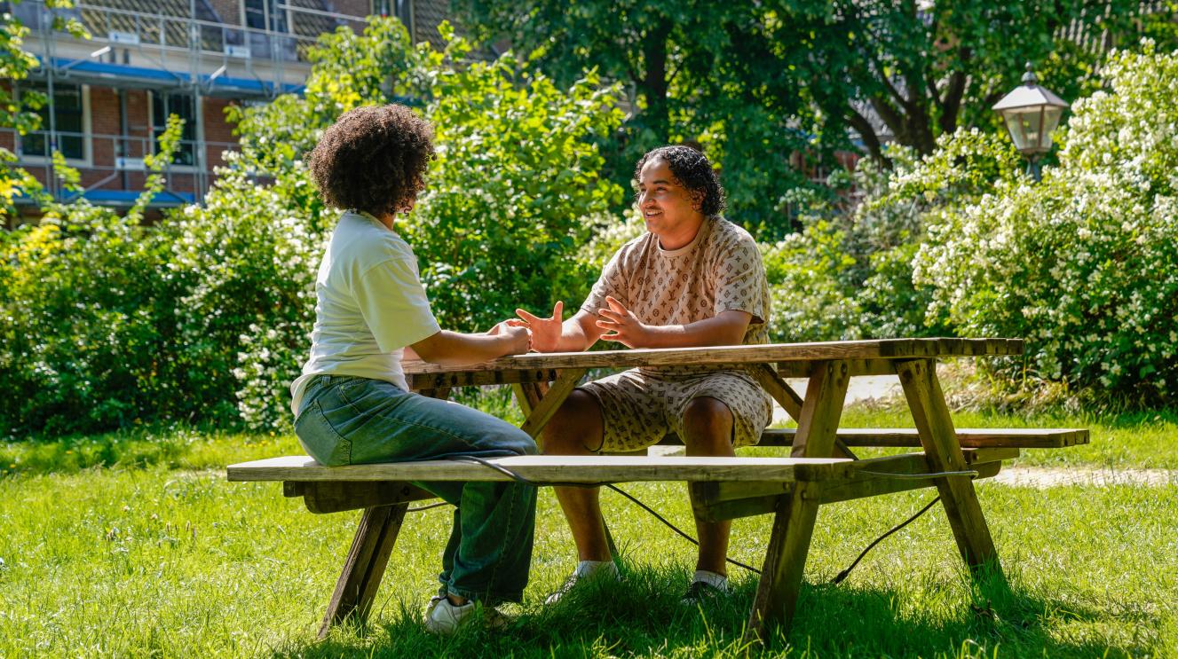 Twee jongeren in gesprek aan een picknicktafel