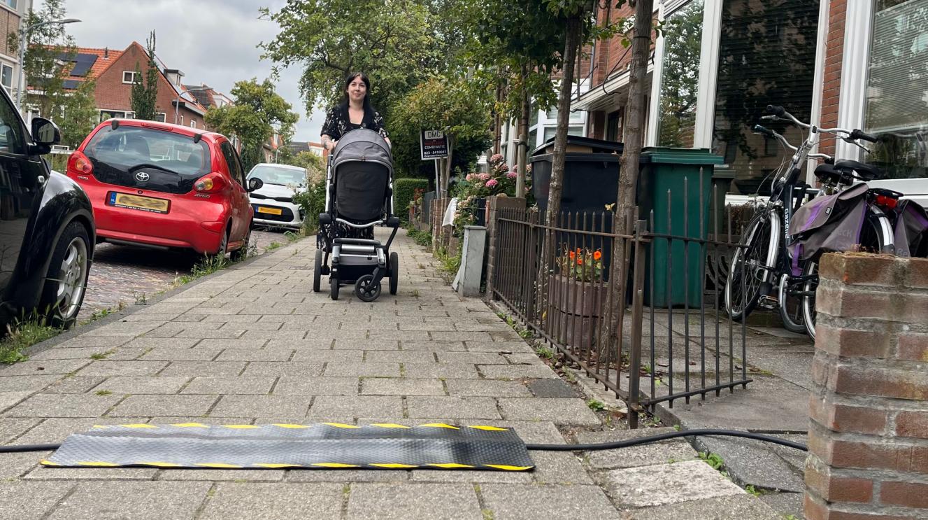 Vrouw loopt met kinderwagen richting een kabelmat