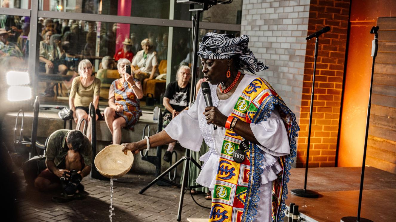 Ceremonieleider doet een Surinaams ritueel. 