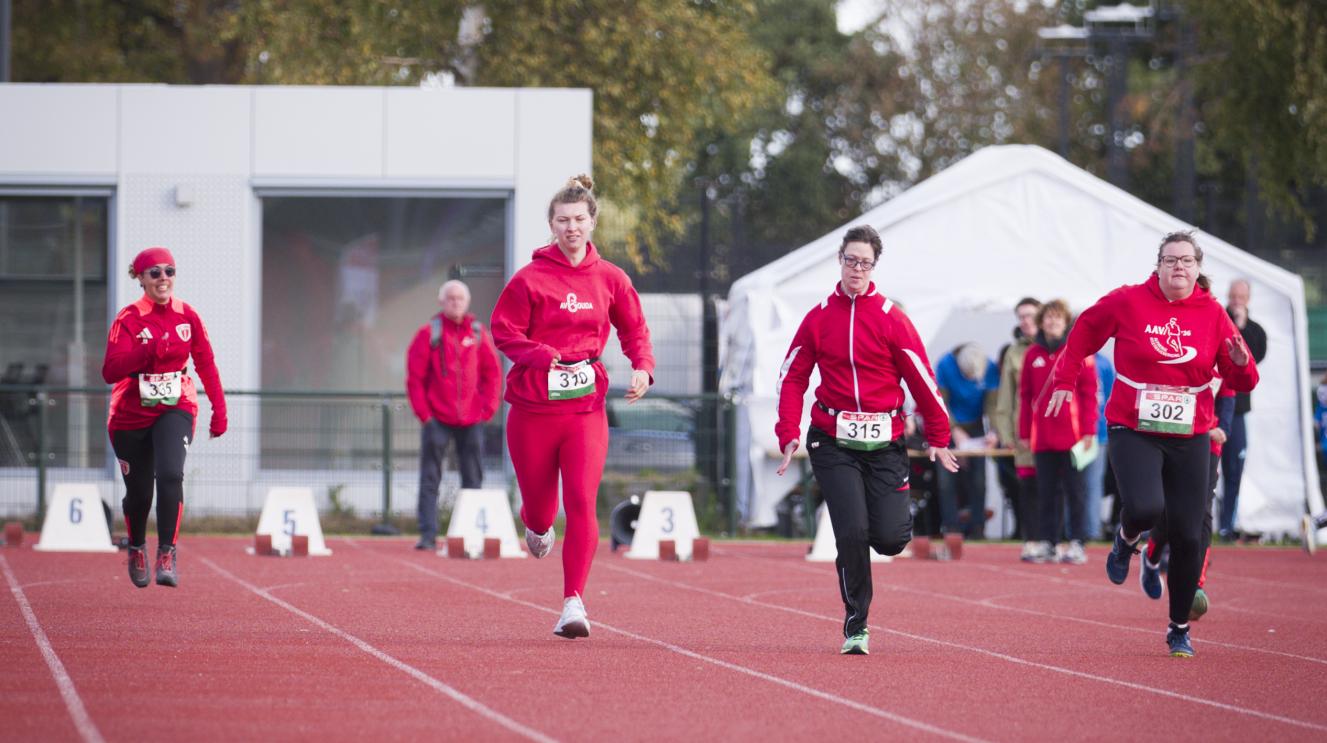 3 hardlopers lopen over het sportveld. 