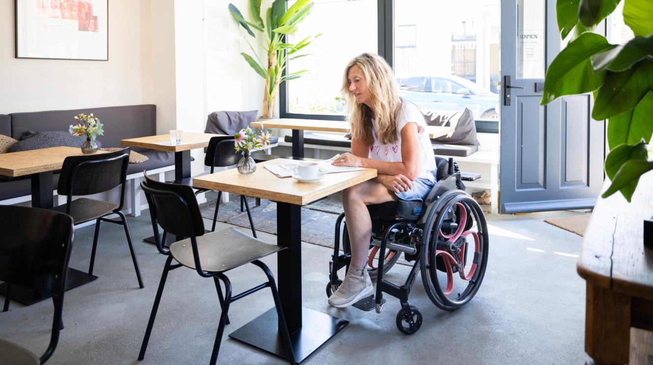 Vrouw in rolstoel in café
