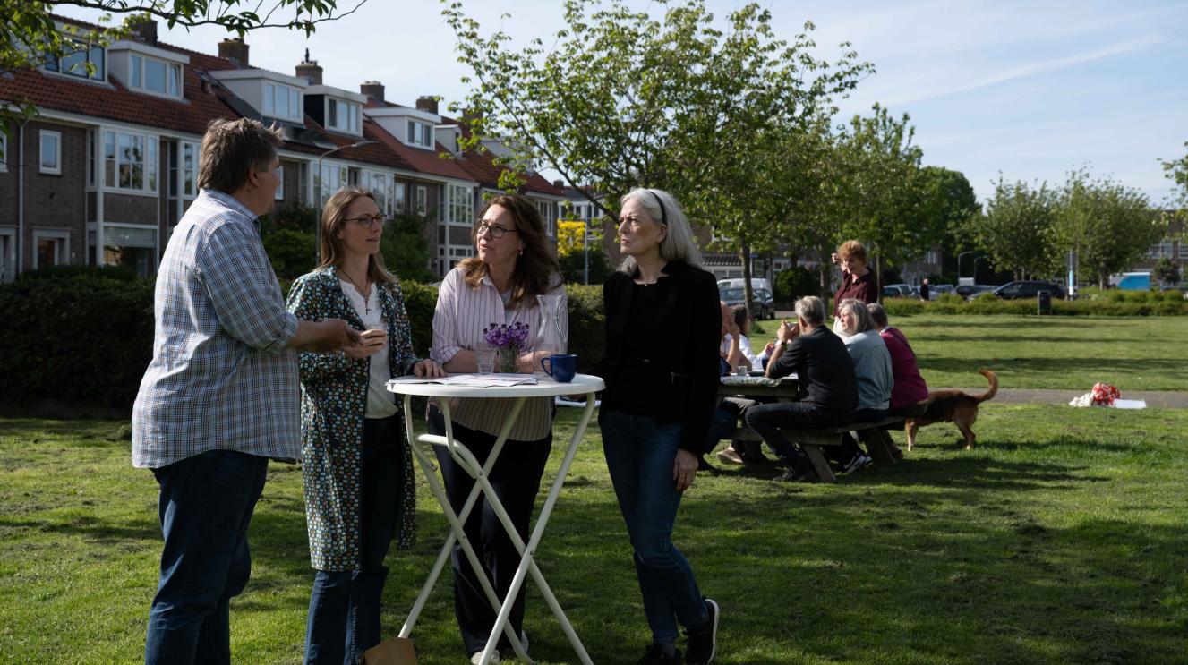 Buurtbewoners buiten in gesprek aan statafels