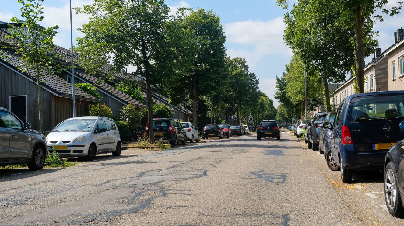 De afbeelding laat een straat in de Zuiderpolder zien, waar veel onderhoudsbehoefte aan de weg zichtbaar is. 