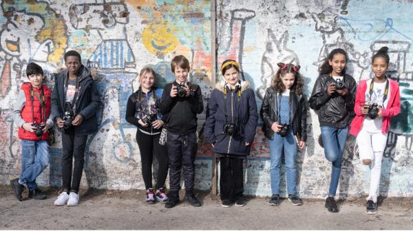 Jongeren met camera's tegen een muur. 